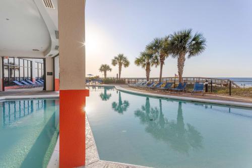奥兰治比奇奥兰治比奇恒庭套房酒店的一座棕榈树和海洋的大型游泳池