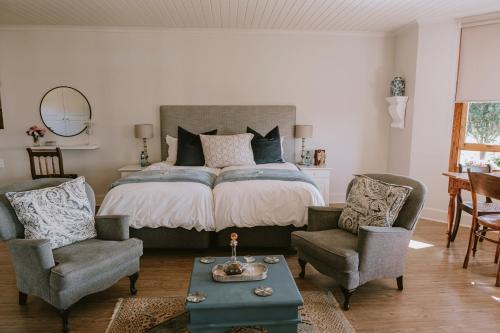 Curryʼs PostThyme Out Weltevreden Farm的一间卧室配有一张带两把椅子和一张桌子的床。