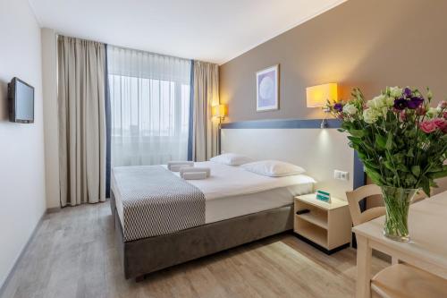 克莱佩达Aurora Hotel Klaipeda的配有一张床和花瓶的酒店客房