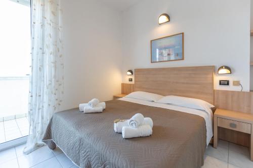 里米尼格罗布斯酒店的一间卧室配有一张大床和毛巾