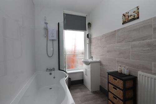 克利索普斯Executive Sea View apartment 3 Bedroom 'Lodge with the Legends' Sleeps up to 8的白色的浴室设有浴缸和淋浴。