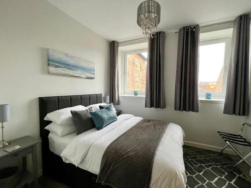 林利斯戈Central Apartment Linlithgow的卧室配有带枕头的床铺和窗户。