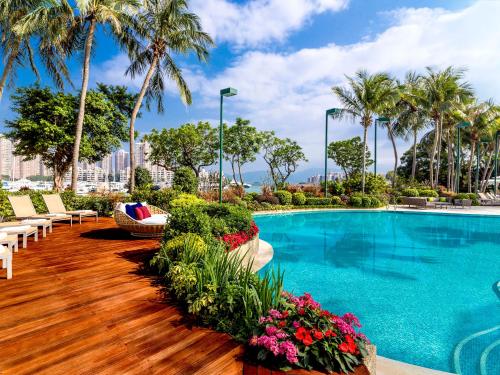 香港香港黄金海岸酒店的一座带椅子和鲜花的游泳池,棕榈树