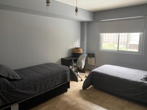 门多萨Oasis 1.6的一间卧室设有两张床、一张桌子和一个窗口。