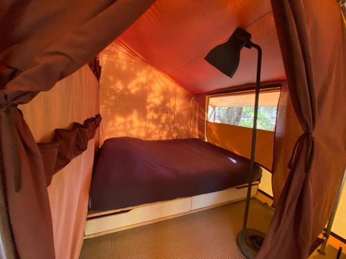卡尔康Camping la Kahute, tente lodge au coeur de la forêt的小房间,帐篷里配有一张床