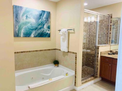 奥兰多Walking Distance from Universal One Bedroom Resort的带浴缸的浴室和墙上的绘画