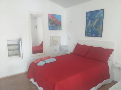 布希奥斯玛吉奥萨维拉宾馆的卧室配有红色的床,墙上挂有绘画作品