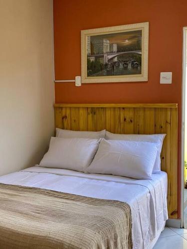 贝洛奥里藏特Aconchego Mineiro com Garagem的卧室内的一张床位,卧室内拥有橙色的墙壁
