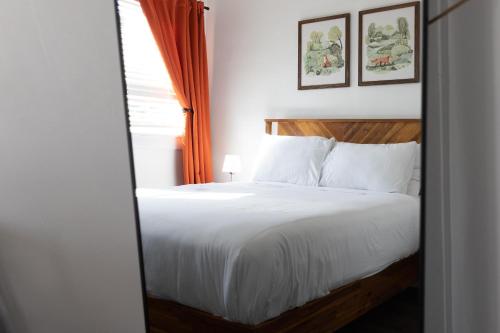 圣克卢亨特阿姆斯酒店的卧室配有白色的床和橙色窗帘