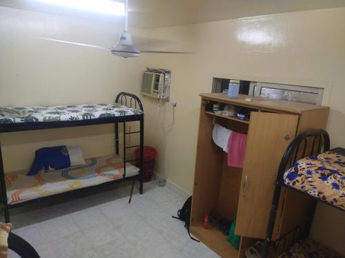 沙迦Bed space abu shagara park的小房间设有两张双层床和一张书桌