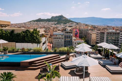 雅典Skylark, Aluma Hotels & Resorts的一个带椅子和遮阳伞的屋顶游泳池和一个城市