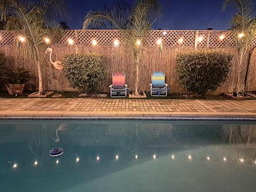 弗雷斯诺Tropical Paradise的游泳池畔的两把椅子晚上