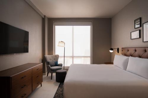 蓬塔卡纳福朋喜来登蓬塔卡纳村酒店的一间卧室配有一张床、一台电视和一把椅子