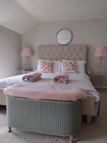 赫尔斯顿Samphire Cottage的一间卧室配有一张大床,上面有粉红色的毛巾