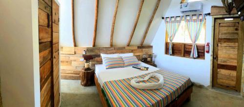 玛雅湾Kin Resort Lodge的一间卧室配有一张带条纹毯子的床和窗户