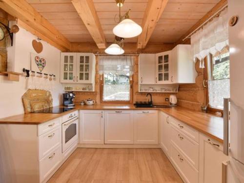 乌斯特龙Świerkowy Raj的厨房配有白色橱柜和木制天花板