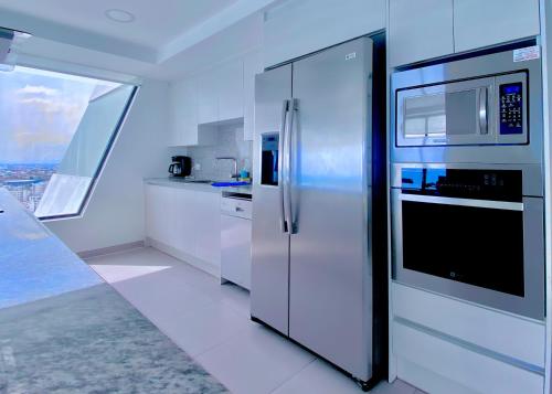 曼塔The Best Luxury Penthouse - Beach View的白色的厨房配有冰箱和微波炉。
