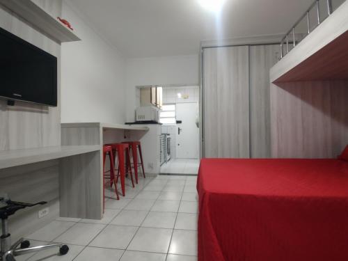 桑托斯Studio completo frente à Praia do Gonzaga ( Pé na Areia )的一间带红色床的卧室和一间厨房