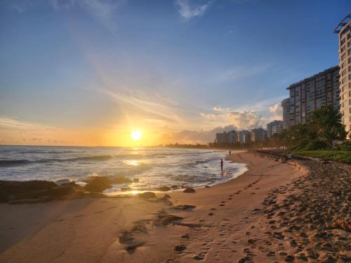 圣胡安Breathtaking 2-Bedroom Beachside Apartment的日落时分的海滩与海洋和建筑