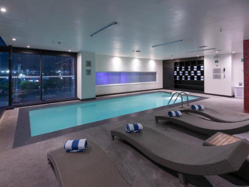 普埃布拉普埃布拉华美达安可酒店的一座带椅子的游泳池和一座游泳池