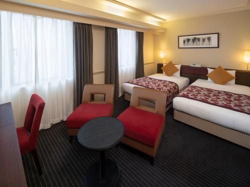 上越市ART 上越酒店的酒店客房带两张床和一张桌子以及椅子。