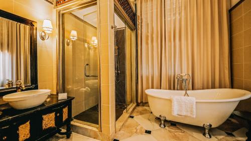 琅勃拉邦JingLand Hotel Luangprabang的带浴缸、水槽和镜子的浴室