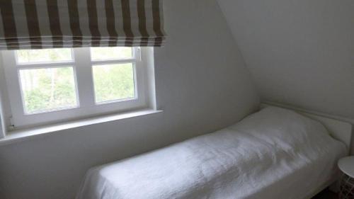 圣彼得奥尔丁Reetdachhaushaelfte-1的一间小卧室,配有床和窗户