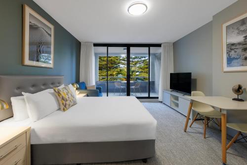 克罗纳拉奎斯特克鲁海滩酒店的一间卧室配有一张床、一张书桌和一台电视。