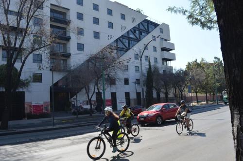墨西哥城Right @Reforma - Beautiful condo with 2 balconies的三人骑着自行车沿着街道行驶,街道上有建筑