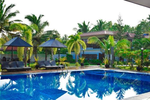亭可马里绿色花园酒店的房屋旁的游泳池配有椅子和遮阳伞