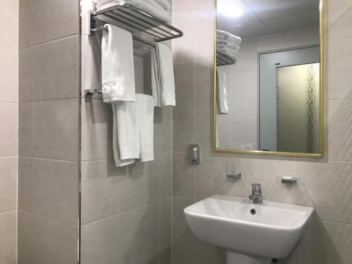 西归浦市Primula Hotel - Formerly Sanbangsan Hotel的白色的浴室设有水槽和镜子