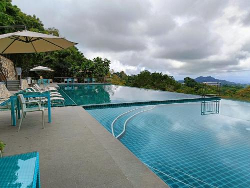 宿务Mist Mountain Resort powered by Cocotel的一个带桌子和遮阳伞的游泳池