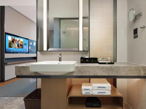 深圳深圳宝安机场希尔顿欢朋酒店的一间带水槽和镜子的浴室以及一台电视