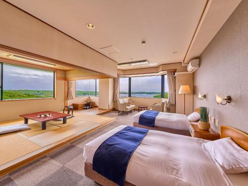 志摩市Yukai Resort Premium Shima Saichoraku的酒店客房设有两张床和一张桌子。