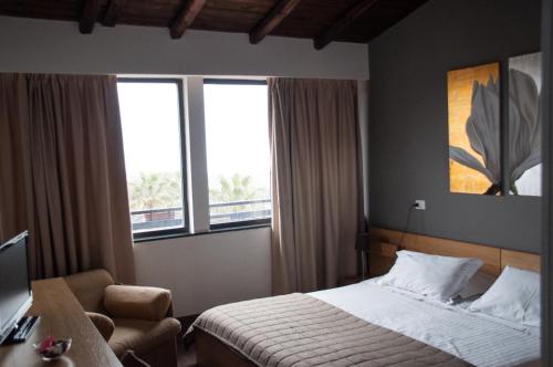 尼科洛西米开朗基罗别墅酒店的一间卧室配有一张床和一把椅子,还有两个窗户