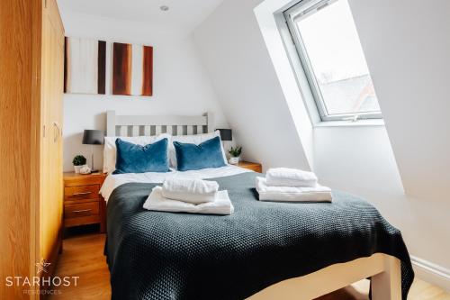 纽伯里Central 3 bed apartment at Regents Court, Newbury的一间卧室配有一张带蓝色枕头的床和一扇窗户。