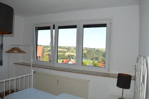 阿布斯贝格Gemütliches Apartment am Brombachsee mit Seeblick.的白色客房的三扇窗户享有美景