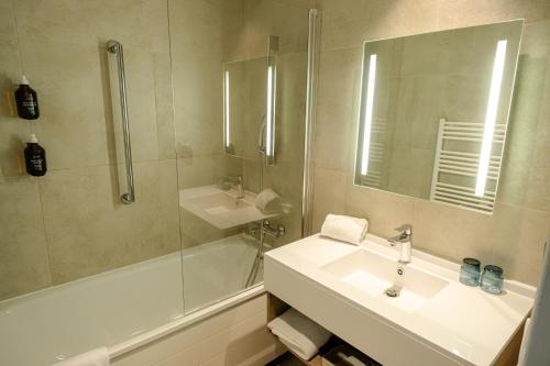 夏蒙尼-勃朗峰Big Sky Hotel的浴室配有水槽、淋浴和浴缸。