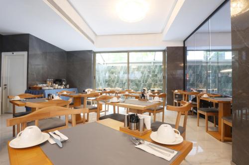 伊兹密尔Riva Hotel Alsancak的餐厅设有木桌、椅子和窗户。