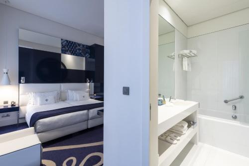 里斯本葡萄牙精品酒店的一间卧室配有一张床、一个浴缸和一个水槽