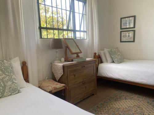 Bathurst金士顿农场旅馆的一间卧室设有两张床、一个梳妆台和窗户。