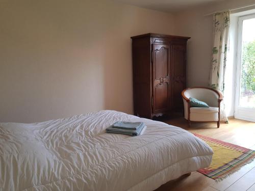 Maison La Petiote的一间卧室配有一张床、一个橱柜和一把椅子