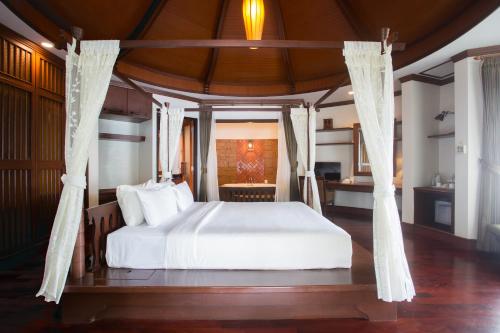 奥南海滩金海滩度假酒店的一间卧室配有一张带白色床单和窗帘的床