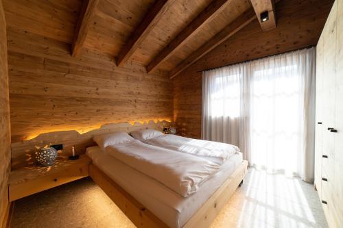维尔德豪斯Chalet Zuestoll的卧室配有木墙内的一张床