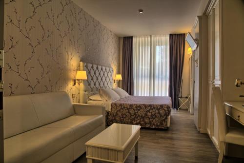 雷卡纳蒂Hotel Palazzo Bello的酒店客房设有一张沙发和一张床