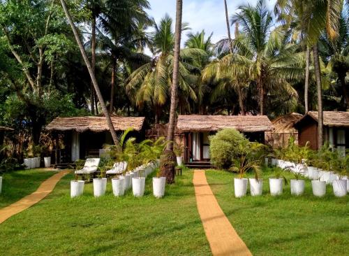 曼德姆Mamagoa Beach Resort的度假村设有白色椅子和棕榈树