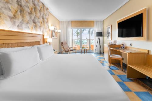 卡勒达德福斯特Elba Sara Beach & Golf Resort的酒店客房设有一张大床和一张书桌。
