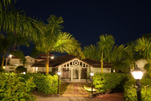 兰纳加Beyond The Corbett Tales Resort and Spa的一座棕榈树在晚上的房屋