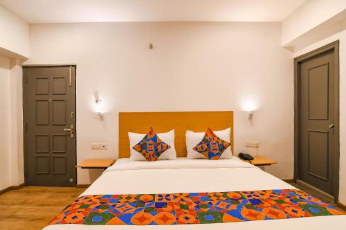 加尔各答FabHotel Sayeeda International的一间卧室配有一张带色彩缤纷枕头的大床