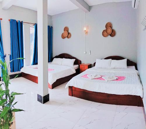 贡布Kampot Nature Villa Resort的一间卧室配有两张蓝色窗帘的床